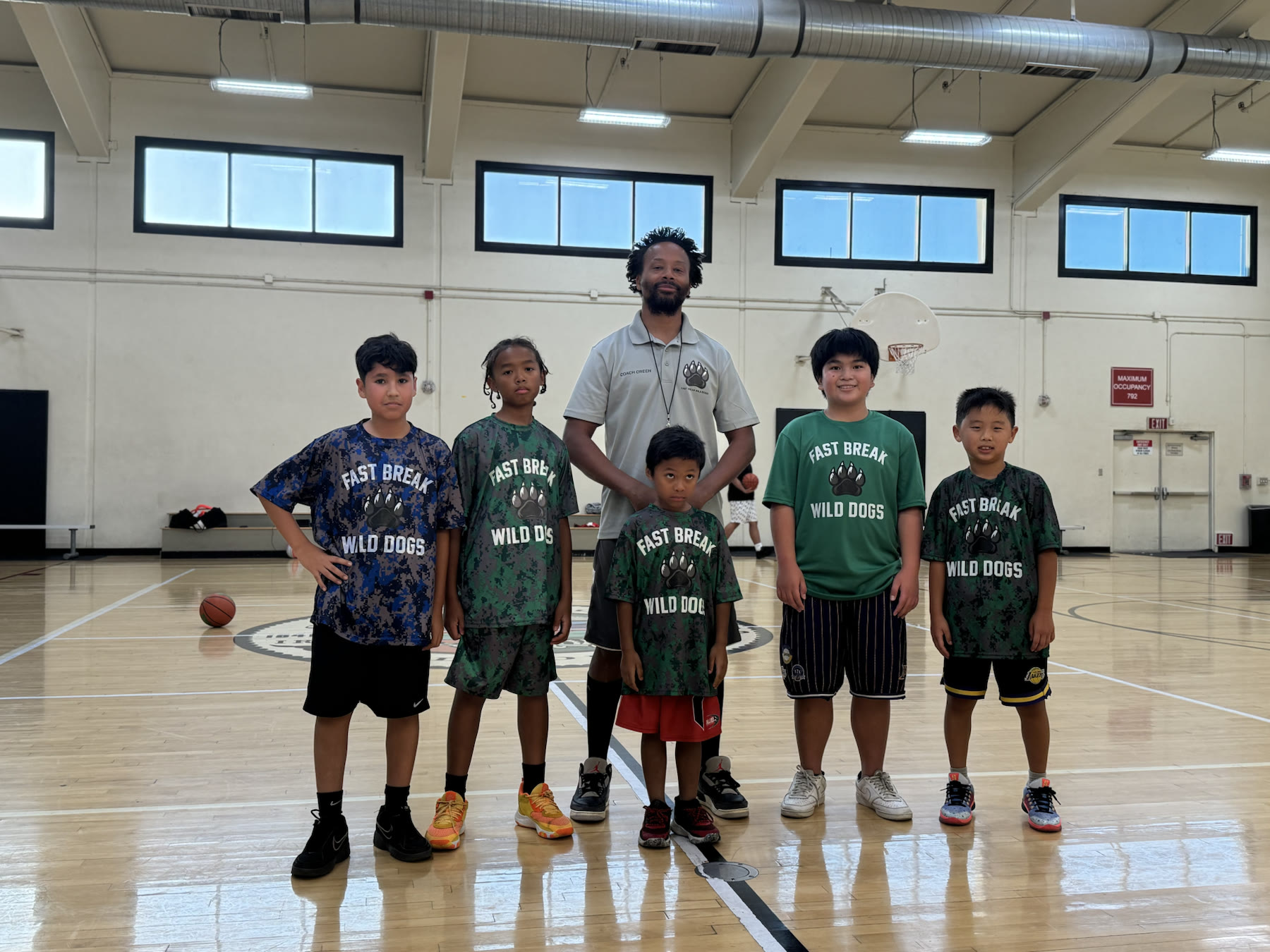 Coach LaShaun Green standing with five young basketball players in a gym