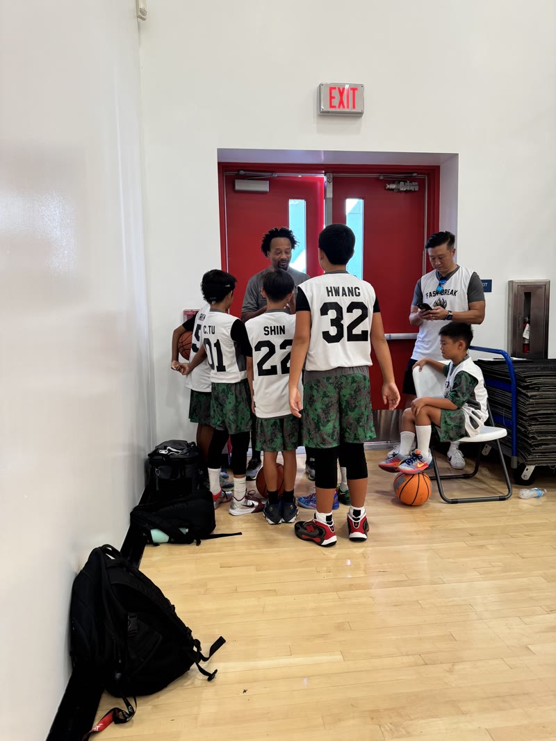 Coach Green speaking with Fast Break Wild Dogs youth players beside the court