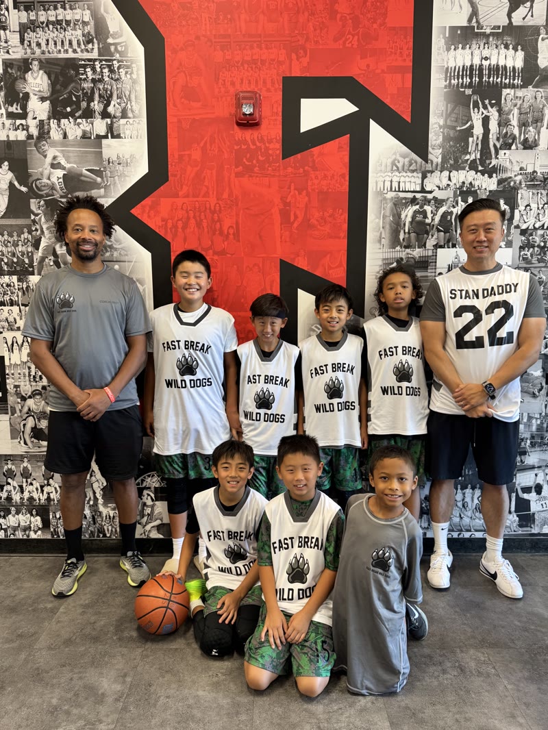 Coach Green, another adult, and Fast Break Wild Dogs youth players posing together during an 11U game day